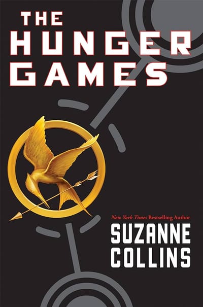 A black background with a gold pin on it. The pin has a mockingjay holding an arrow encircled by an elongated bow.